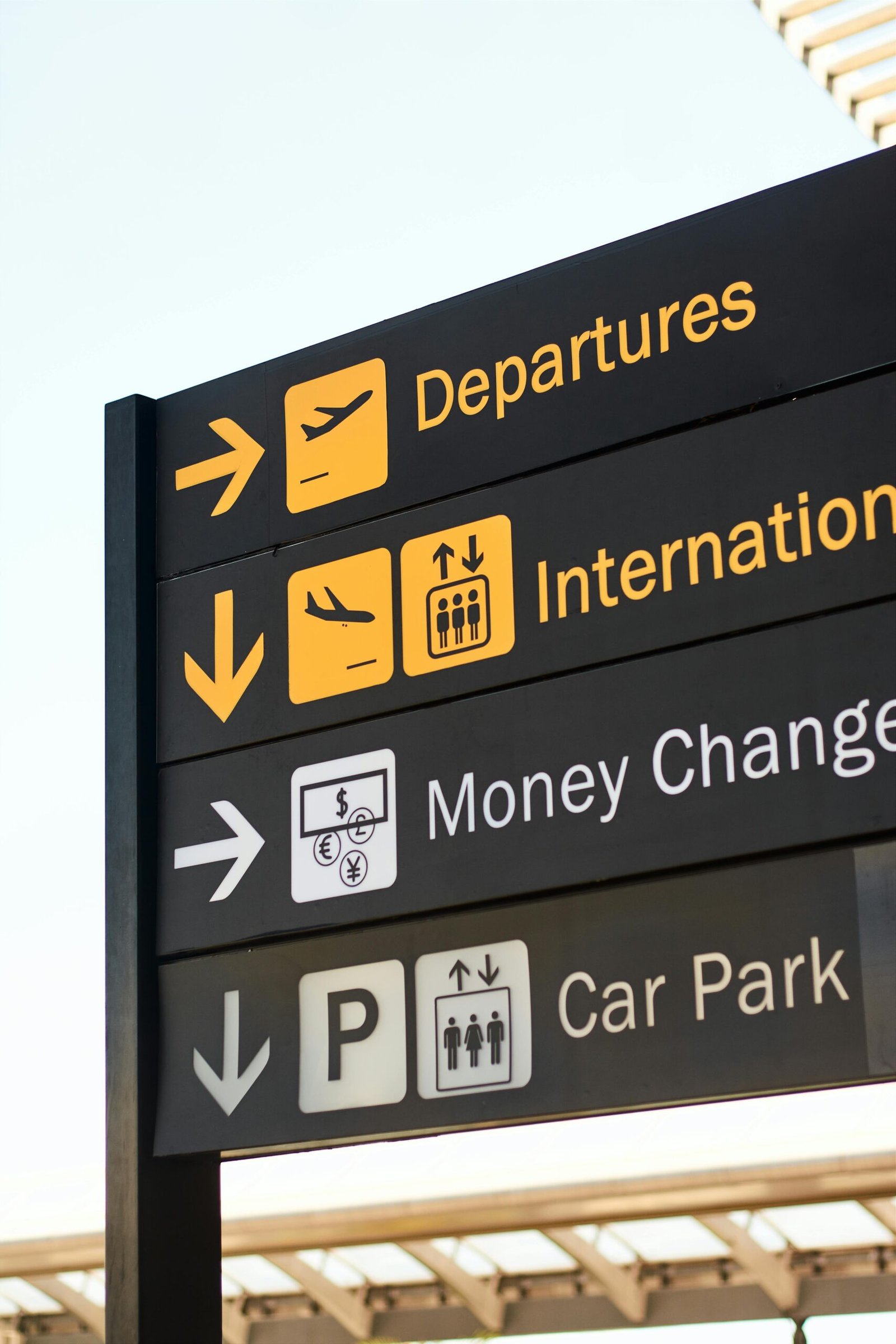 Close-up of airport direction signs for departures, international, money change, and car park.