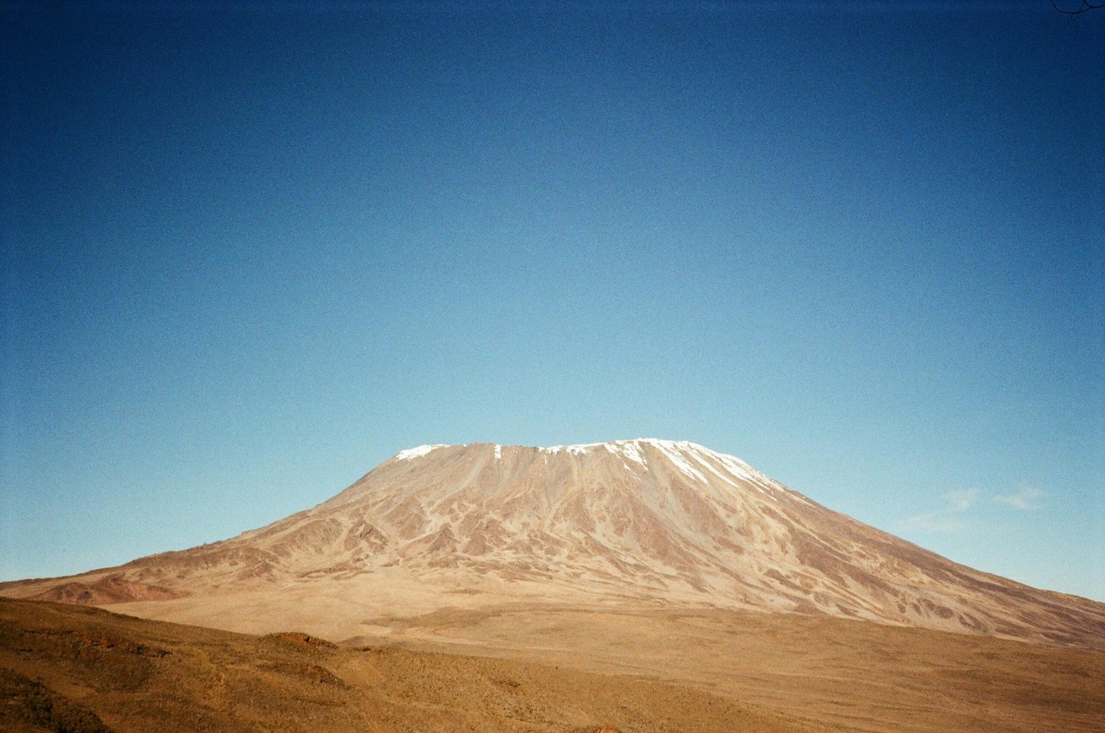 Stunning capture of Mount Kilimanjaro with its snowy peak against a clear blue sky in Tanzania.