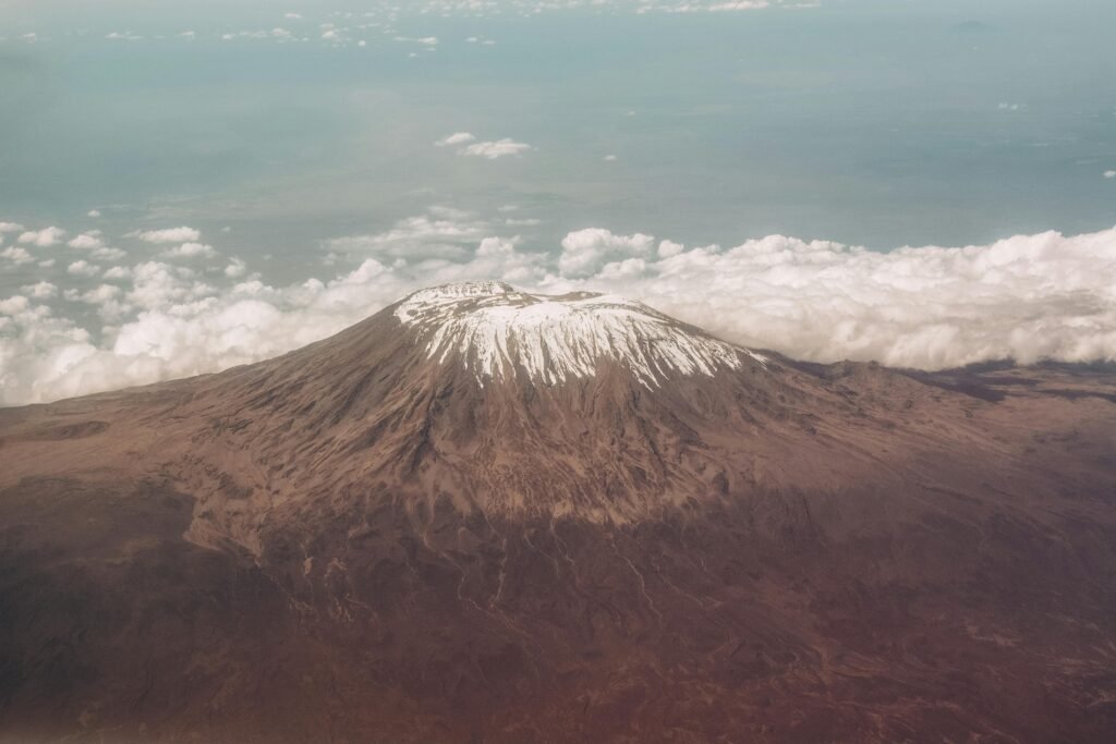 Breathtaking aerial view of Mount Kilimanjaro's snow-capped peak surrounded by clouds.